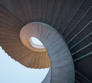 Low angle shot of curved spiral stairs under a bright blue sky